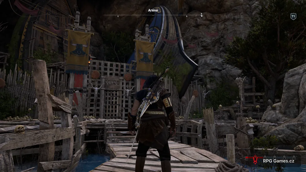 Vstup do arény v Pephce v Assassin's Creed Odyssey — dřevěná brána u skal